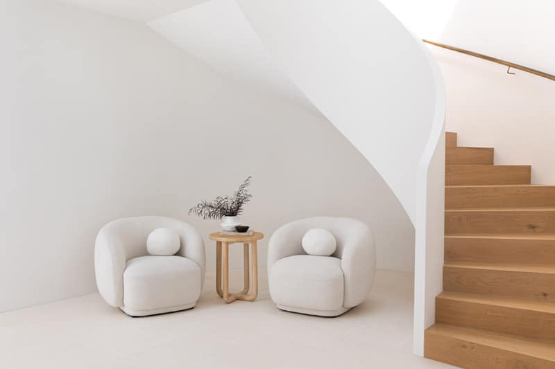 two white arm chairs next to a spiral stair case.